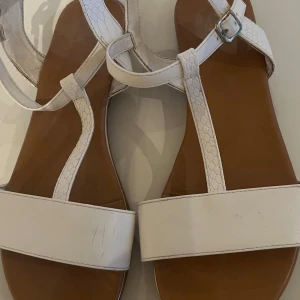 Vita sandaler - Jag säljer ett par vita sandlale från dinsko(tror jag), perfekt till skolavslutning och sommaren. Sandalerna är i relativt gott skick och endast använda under en sommar. Spänner på ena skon är lite smått tråkigt, men det går säkert att fixa till!🥰