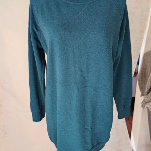 Blå långärmad tröja från H&M - En enkel och bekväm blå långärmad tröja från H&M:s Basic-kollektion. Tröjan har en rund halsringning och ribbstickade muddar vid ärmslut och nederkant.