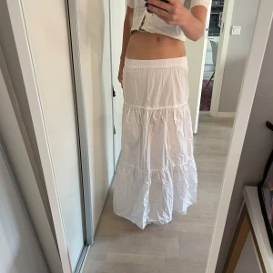 Vit långkjol - Vit långkjol från gina tricot. Köpt för 500kr. Använt fåtal gånger. Går nästan ner till marken till mig (175cm). Den är lite genomskinlig, men inte mycket. Har en liten fläck på framsidan, men går förmodligen bort i tvätten.