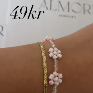 Två armband - Ett vackert armband med små vita och rosa pärlor formade som blommor. Perfekt för att ge en elegant touch till din outfit.