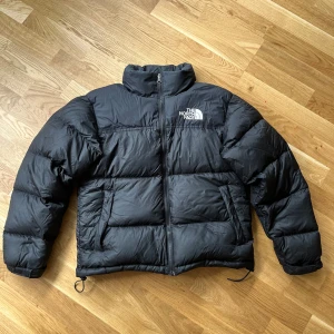 The North face dunjacka Svart - Svart The North face dunjacka i storlek S. Har använts flera gånger men är i väldigt bra skick. Jackan har även en uppfällbar luva i kragen ifall det skulle regna. 🖤 Mått:  Defekt: Ett ihopsytt hål på vänster ärm, Bild 5