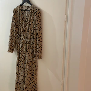 Maxiklänning - Lång prickig klänning med v-ringning. Knytskärp i samma tyg o resår i midjan