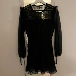 En svart kort prickig långärmad klänning i mesh med volang över axlarna, framtill och nedtill samt resår i midjan och vid ärmslut från H&M i strl XS!💓 