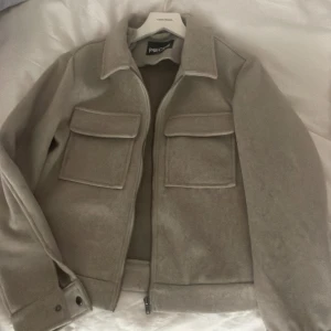 Beige jacka - Beige tygjacka i storlek L men mer som en M. Från Vero Moda, använd fåtal gånger i fint skick. Knappar vid ärmarna.