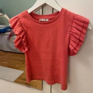 Volang topp från Zara - Super fin volang topp från Zara. Den är korallrosa och i super bra skick. Jag säljer för att den är lite för liten. Köparen står för frakt.