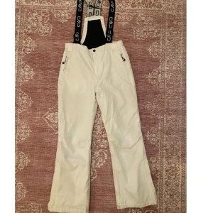 Vita skidbyxor / täckbyxor  - Såå snygga vita skidbyxor / täckbyxor i hardshell-yttermaterial ⭐️ I barnstorlek men passade som strl 32-34💛 Med hängslen samt gylf i midjan <3 Svagt missfärgade på insidan av bensluten längst ner, men syns knappt 💛