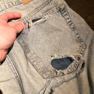 Slitna jeans - Coola slitna högtmidjade jeans i storlek 42. Ripped i bakfickorna och under höger rumpa. 