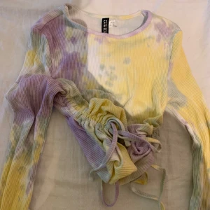 Tröja med snören på sidorna  - Tröja i fyra blandade färger med snören på sidorna som man kan spänna 