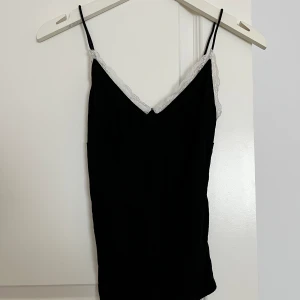 Svart topp med spets  - En svart gullig topp med vit spets upp till, knappt använt 