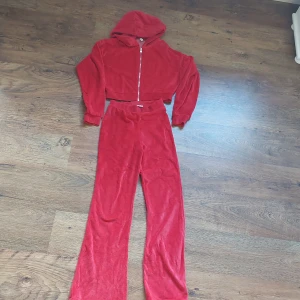Mjukisset - Oanvänt rött mjukisset, högmidjade byxor i XS och kort zip up hoodie i Small. Mjuk och skönt.