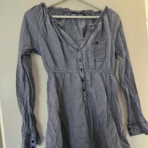 Tunika/blus - Nyskick längre modell tunika/blus med bröstficka ,knappar och resår i midjan, dock står det ej strl men passar en som har 36-38. Den är blå/vit rutig. Se sista bilden. Katt finns I hemmet