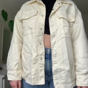 Krämvit jacka - En krämvit jacka som passar till våren eller sensommar. Den är tunn men inte jättetunn då den är lite fodrad. Fyra Fungerande fickor. Ingen dragkedja, endast knappar. Har knappar vid ärmen. Den är oversize. Mycket bra skick. 