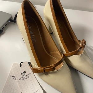 Beige klackar med brun rosett - Helt nya och oanvända, dock sliten vid siden pga taggen. Osäker om storlek men jag har 36-37 och den passar precis!  Passar perfekt till balen eller vilken klänning som helst. Kommer inte med skobox.  Kontakta vid frågor 🎀