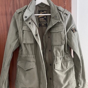 Superdry M65 vintagejacka - säljer min sjukt snygga superdry jacka som är köpt förra sommaren på superdrys butik i göteborg. skicket är toppenbra, i princip som ny då jag använt den 2 gånger. den kommer inte till användning då jag inte tycker den passar mig i stil! nypris: 1200