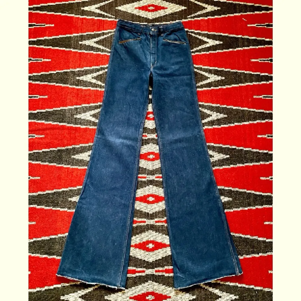 Asballa jeans med läderdetaljer av Las Vegas på 70-talet. Bra skick, några stygn saknas på höger bakficka och färgen har blött in på mocka-lappen i bak.  Midja 34cm Höfter 43cm Gren 28cm Längd 120cm Innersöm 92cm Ofållade byxben  100% bomull. Jeans & Byxor.