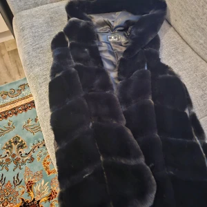 Päls väst - Ny skick. Svart väst, väldigt varm. Har knappar, luva. Nypris 2000