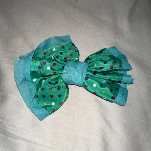 Hårspänne med stor grön rosett - Säljer detta fina hårspänne med stor grön rosett på eftersom att den inte har använts på länge.  Rosetten har en massa fina, gulliga detaljer på sig, så detta hårspänne är perfekt för att klä upp sig till vadsomhelst, eller bara för att, helt enkelt✨