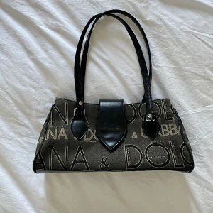 Vintage Dolce & Gabbana  - Fin vintage väska. Bra skick, några enstaka slitskador i hörn men axelbanden är fina. Sitter snyggt på axeln. Två stora fack med blixtlås. Svarar gärna på frågor. 