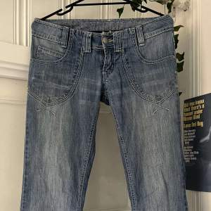 Jätte fina lågmidjade bootcut/utsvängda ljusblåa jeans med snygga broderi detaljer på både fram och baksidan. Är i mycket bra skick förutom att dom är uppsprättade nedtill som du ser på sista bilden❤  Midja-37 cm Höfter-46 cm Total längd-110cm