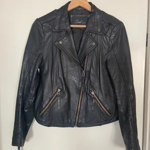 Skinnjacka  - Skinnjacka i bikermodell.  Har ett litet märke på ryggen, se bild☺️ Fodret i ena fickan är trasigt men fickan går att använda ändå, alternativt kan man sy.  