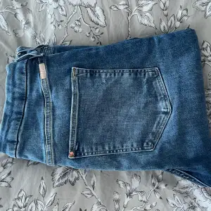 Blåa jeans med slitningar nere vid ankeln  Nyskick
