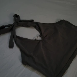 Grå halter neck top med hjärta - Superfin halter top i mörkgrå med en hjärtdetalj i mitten och ärmar man knytar själv, helt oanvänd🩶🩶