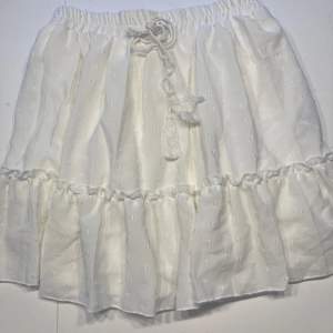 Fin vit kort kjol med insydd underkjol. Resår i midja.  Använd endast 1 gång, nyskick! 