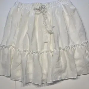 Fin vit kort kjol med insydd underkjol. Resår i midja.  Använd endast 1 gång, nyskick! 