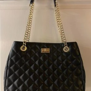 Isabella Rhea handväska - Svart kiltad handväska från Isabella Rhea med gulddetaljer.  Nypris 1200:-