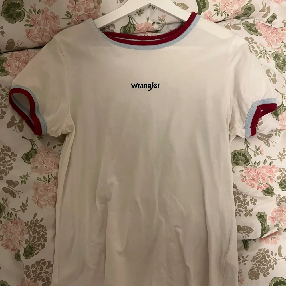 En vit T-shirt från Wrangler med färgade ränder. Använd 1/2 gånger, så i jättebra skick. Storlek M/38. T-shirts.