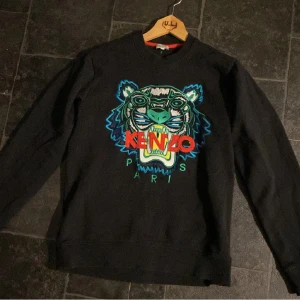 Svart tröja från Kenzo med tigerbroderi - En svart tröja från Kenzo med ett färgglatt tigerbroderi på framsidan. Tröjan har långa ärmar och en normal passform.