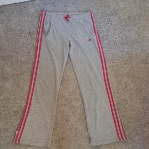 Adidas byxor - Gråa adidas byxor med rosa ränder. Är köpta på vinted men hr inte andvändit dom då dom är för korta på mig ( jag är 172cm). Skriv gärna vid frågor☺️