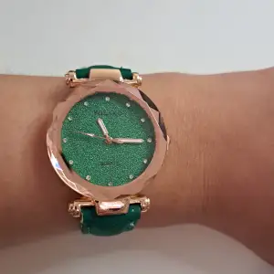 This is a new arm watch that have green straps and elegant gold atached to it. 