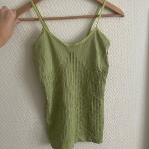 Limegrönt linne - Fint limegrönt linne i samma mjuka/stretchiga material som dansdräkter! Har små hål i som syns jättefint när man har linnet på sig. Köpt på Humana! Står ingen storlek men skulle gissa på en S. 