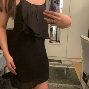 Kort svart klänning med liten design  - Tunn svart klänning med flowy detalj vid framsidan av klänningen, lite kort.   29kr frakt 💕