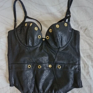 Korsettopp fakeläder 75C - Fin "korsett" från Myleene Klass 🖤 Köpt från Beyond Retro. Storleken på kupan motsvarar en 75C. Nedsatt pris då tidigare användning har gjort att beningen inte håller formen ordentligt, så den ger inte "stöd" som en äkta korsett.