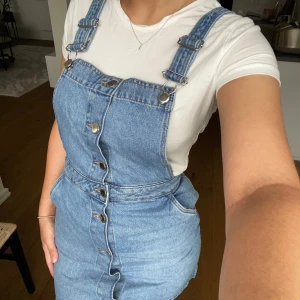 Hängselklänning  - Justerbara hängselklänning. Knapparna framtill går att knäppa av. 