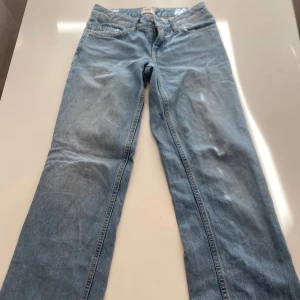 Ljusblå jeansbyxor - Ett par ljusblå jeansbyxor i normal passform. Byxorna har en klassisk design med fem fickor och knappgylf.