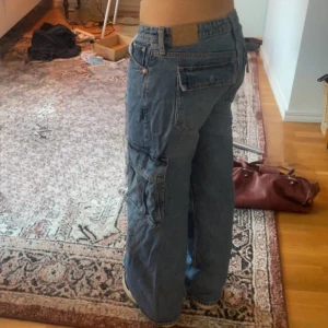 low rise baggy cargo jeans - lågmidjade, baggy, cargo jeans från weekday i modellen trouble. Jeansen säljs inte längre och är köpta för ca 2 år sen men har inte fått mycket användning och är i gott skick. skriv för fler bilder, frågor eller mått💕 original pris 600kr