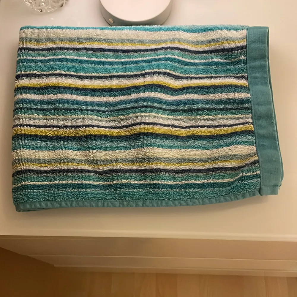 En grön badrummets matta, till det får man även två handdukar. En lite mindre, och den andra vanlig storlek, den lilla är helt turkos, och den stora är både mörkblå,turkos,gul,vit och ljusblå❤️. Övrigt.
