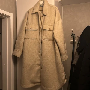 Kappa vit/beige - Vit beige kappa ifrån ginatricot. 2 bröstfickor och 2 ”vanliga” fickor mot höfterna. Användes sparsamt förra vintern. Kommer inte till andvänding längre. Kappan är lite stor och passar även XXL.Kom med förslag på pris om du inte gillar utgångspriset.