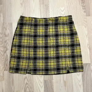 Kort kjol i gulsvart-rutigt mönster från HM Divided i storlek M. Använd enstaka gång. 54 % polyester, 36 % viskos, 8 % polyamid, 2 % elastan. 