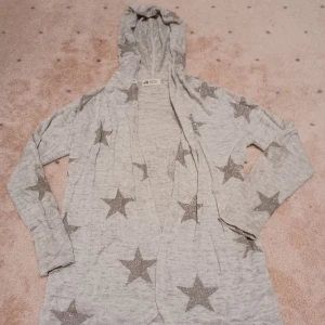 Jättefin grå kofta med glittriga stjärnor  - Säljer nu min fina ljusgrå kofta med glittriga silvriga stjärnor på. Den är sparsamt använd och är därför i toppskick. Storlek 134-140 men passar mig som brukar ha xs eller s. Köparen står för frakten och jag ansvarar ej för postens slarv. 