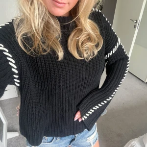 Svar stickad tröja med vita sömmar  - Sjukt cool svart stickad tröja med vita sömmar. Knappt använd köpt för 750kr. Strl M men passar även S beroende på hur man vill att den ska sitta. Från Vero Moda🌸🌸