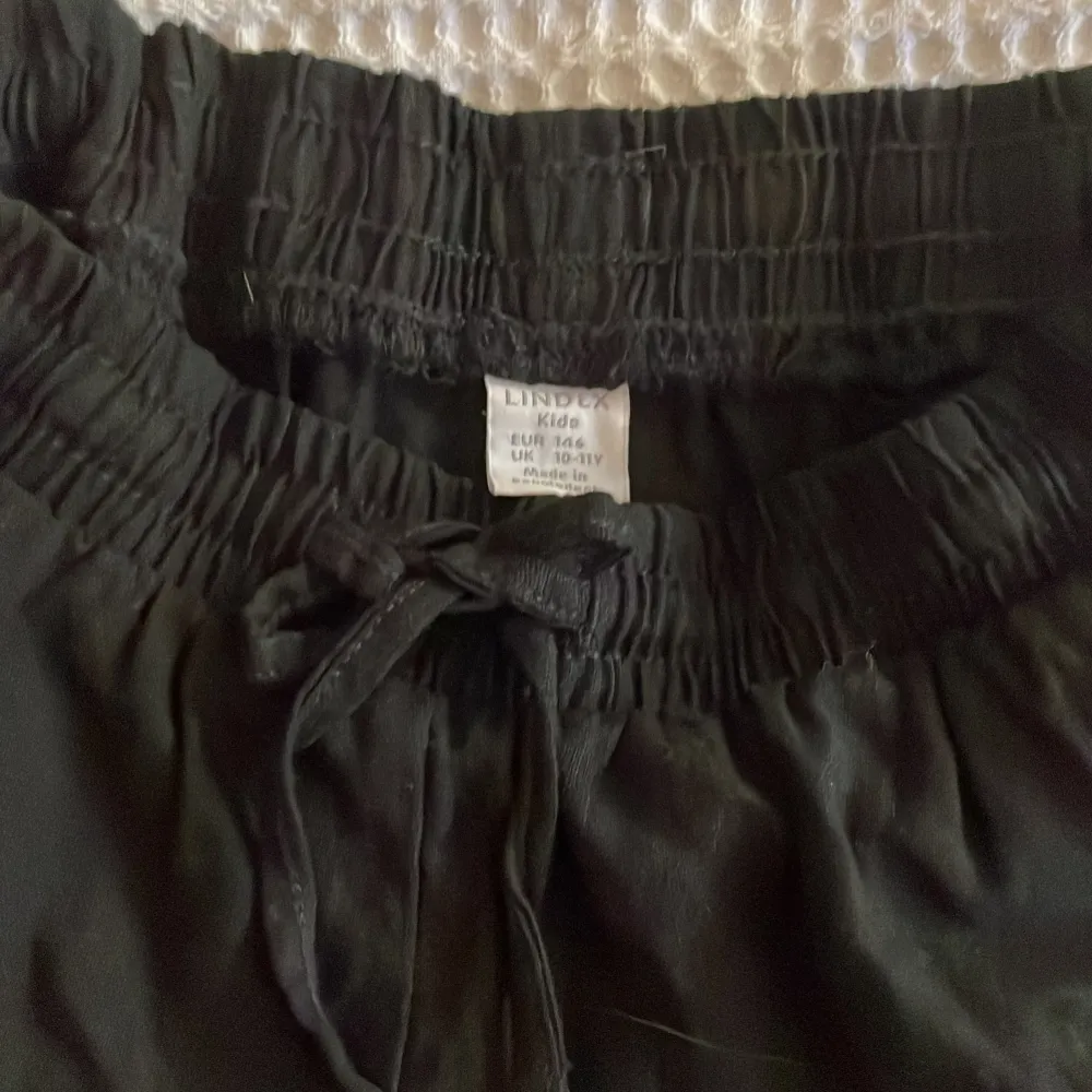 Fina svarta linnebyxor med snören, perfekta till sommar/höst ☀️ I nyskick, använda 1 gång, från Lindex barn i storlek 146. Jeans & Byxor.