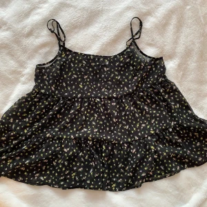 Nytt svart genomskinligt volang linne i strl 38 från HM. - Nytt svart genomskinligt volang linne i strl 38 från HM.  Linnet har reglerbara axelband.  Nytt, aldrig använda   Mått Över bröstet: ca 46 cm Längd från axeln och ner: ca 55-65 cm  100% polyester   Kommer från ett djur och rökfritt hem.