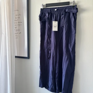 Trekvartsbyxor - Helt nya med prislapp kvar.   Midja: 70cm utan att dra i resåren, 86cm när jag drar. Längd: 83cm