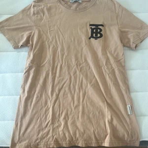 Burberry T-Shirt - Burberry T-shirt i storlek L, passar dock M! Sparsamt använd.