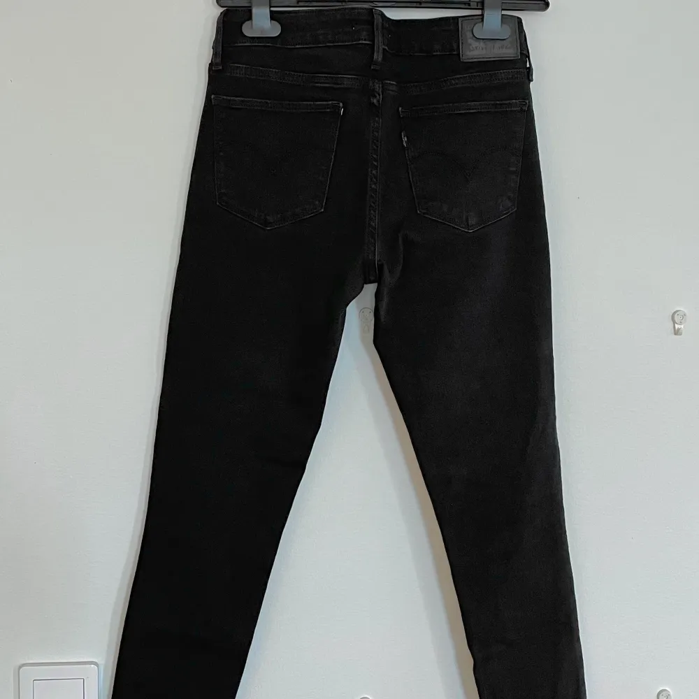 Svarta Levis jeans. Slim fit modell och är i storlek 27/32. Byxorna är klippta några centimeter längst ner. . Jeans & Byxor.