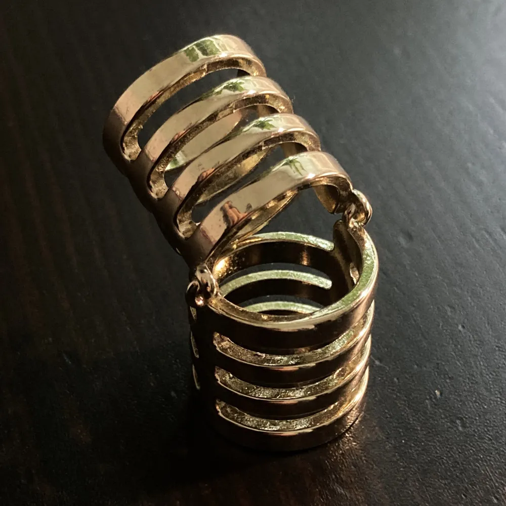 Unik guldfärgad ring med gångjärn. Innerdiameter: 15 & 17 mm, längd: 4,2 cm.. Accessoarer.